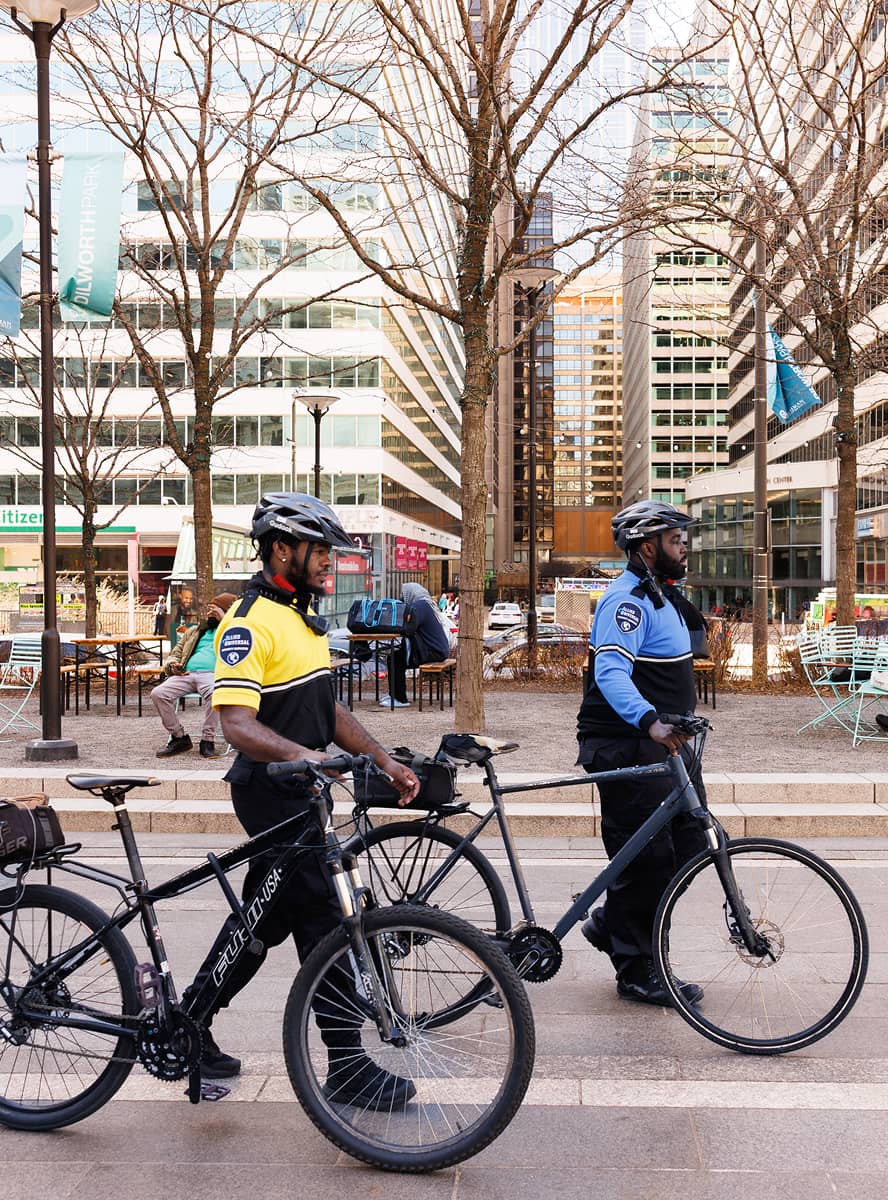 CCD public safety bike patrol officers, wearing yellow and blue uniforms, bike helmets and carrying a 2-way radios, walking their bikes.