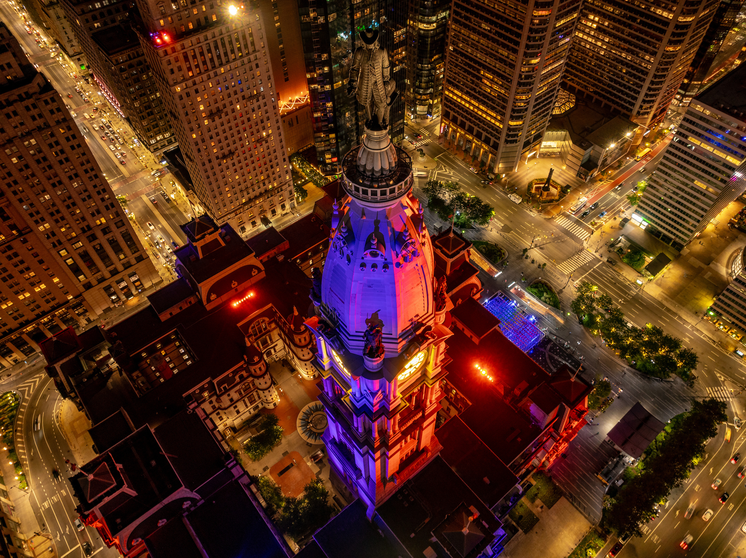 Philadelphia's City Hall lit with purple & red colors at night.